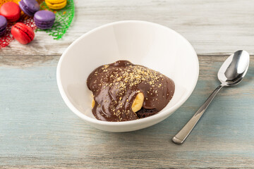 Delicious profiteroles with chocolate sauce on a white porcelain plate