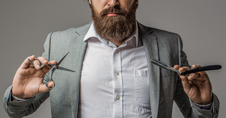 Portrait of bearded man in suit holding barber scissors and straight razor standing. Man, portrait...