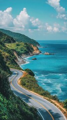 A winding coastal road hugs lush cliffs beside vibrant blue waters under a sky dotted with fluffy white clouds.