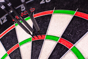 Official dartboard with closeup view of three darts sticking in the Triple 20