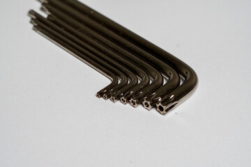 Close-up of L-shaped hex keys with hexagonal tips neatly arranged on a white surface, highlighting...