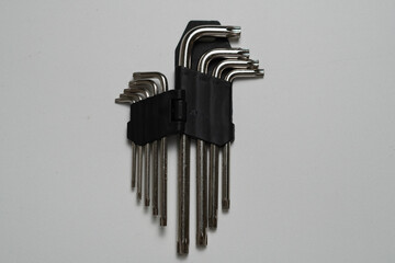 A compact set of silver hex keys neatly organized in a black folding holder, displayed on a plain...