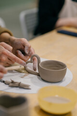 Pottery student modeling clay mug, learning traditional sculpting techniques. Pottery student...