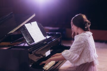 Elegant Woman Playing Piano in Dimly Lit Performance Setting