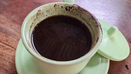 Close-Up of Traditional Javanese Black Coffee in Green Ceramic Cup – Hot, Thick, Sweet Beverage with Visible Grounds