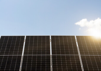 Black solar panels with sunlight on background of blue sky
