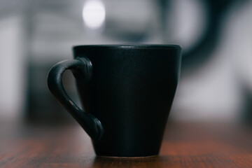 a small, dark-colored espresso cup sitting on a wooden surface