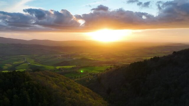Vista aerea di un paesaggio romantico collinare italiano con sole basso e luce calda.