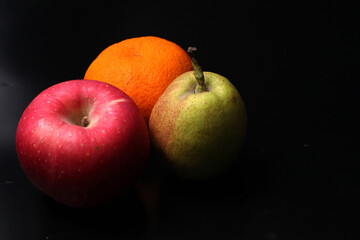 An apple, pear, and orange isolated on black background