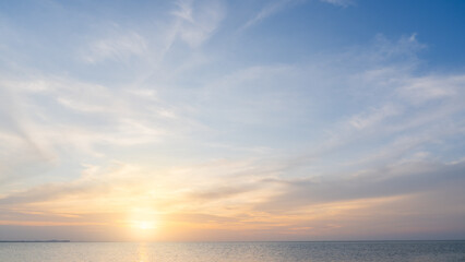Sunset sky clouds over sea in the evening with orange, yellow sunlight, Horizon sea landscape background and sun down in golden hour summer season, Dusk