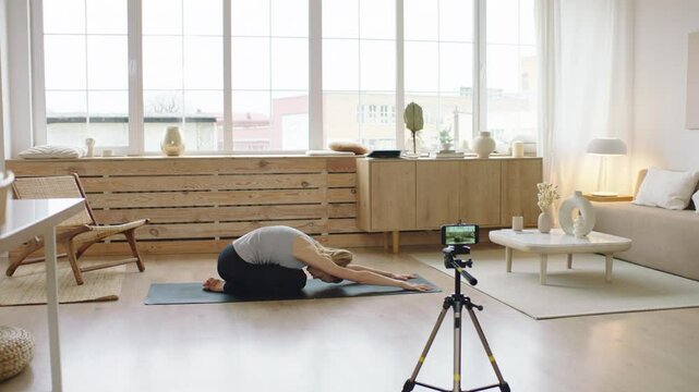 Attractive Caucasian recording making live stream or vlog about doing yoga at home. Stay home, quarantine workout. Shot on ARRI Alexa Mini with Cooke S4 lenses