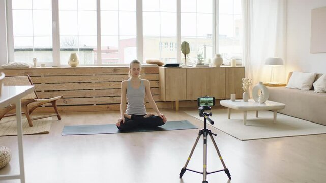 Attractive Caucasian recording making live stream or vlog about doing yoga at home. Stay home, quarantine workout. Shot on ARRI Alexa Mini with Cooke S4 lenses
