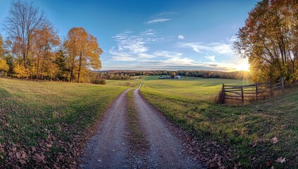 Naklejka premium Serene Country Road Leading Through Vibrant Autumn Landscape with Golden Fields Under Clear Blue Sky at Sunset in Gentle Rolling Hills
