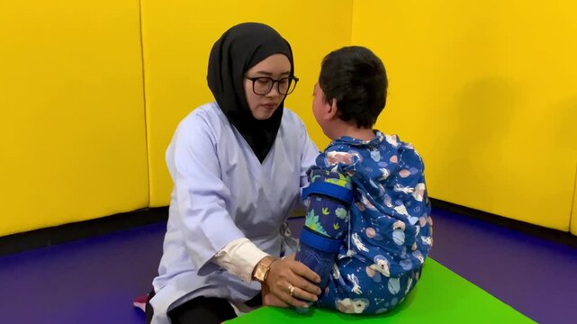 A physiotherapist assists a child living with cerebral palsy in a rehab session. The child wears adaptive braces for mobility support, engaging in therapy to enhance motor skills and movement.