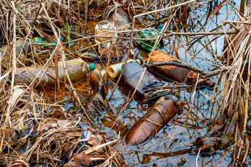 Various kinds of trash waste objects a lot floating in the pond mixed with aquatic plants