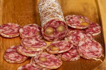 slices of fuet salami with walnuts on a wooden chopping board