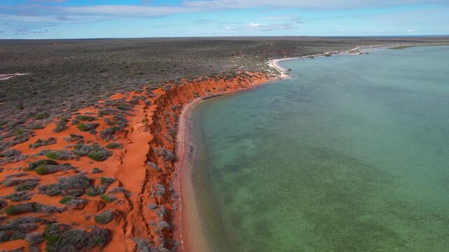 Aerial view of red cliffs and pristine beach along the ocean in Francois Peron National Park, Shark Bay, Australia.
