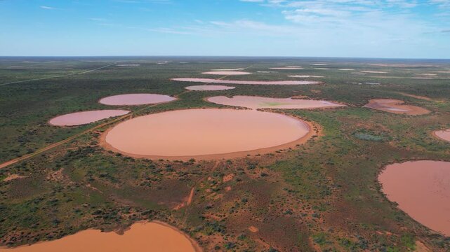Aerial view of semi dry lakes and expansive landscape under a serene sky, Carnarvon, Australia.