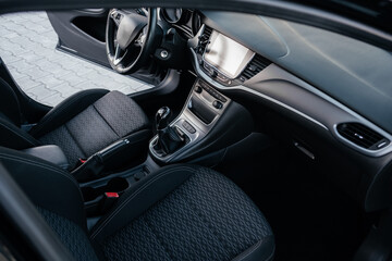 Modern car interior, leather steering wheel, climate control, large navigation screen, fabric on the seats, deflectors on the car panel. Interior details.