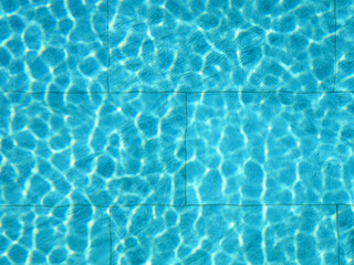 Summer abstract reflection caustics in swimming pool. Blue water surface and ripple wave