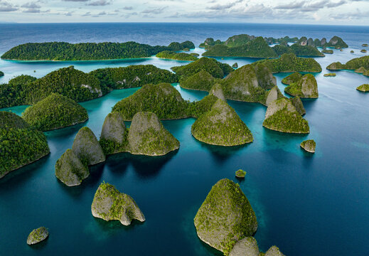 Aerial view of beautiful tropical islands and lush greenery along the serene coastline, Raja Ampat Regency, Indonesia.