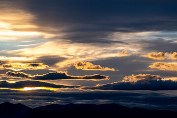 An impressive sunset scene showcasing a stunning sky with silhouetted mountains, blending colors and shadows to create a dramatic and picturesque vista.