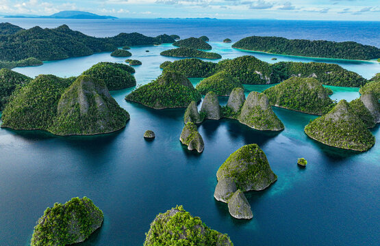 Aerial view of beautiful tropical islands and turquoise lagoon with lush greenery, Raja Ampat Regency, Indonesia.