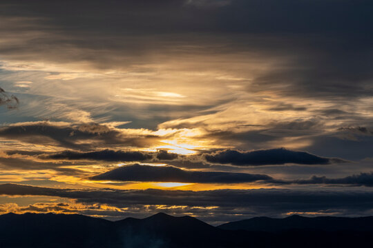 A stunning sunset is highlighted by vibrant colors and unique cloud formations, offering a captivating view over the mountains that evokes a sense of wonder and tranquility.