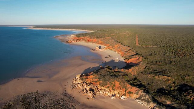 Aerial view of Echo Beach Resort coastline with ochre cliffs and the moon, Broome, Australia.