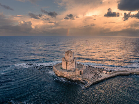 Aerial view of ancient fortress and tower by the beautiful coast and sea at sunrise, Methoni, Greece.