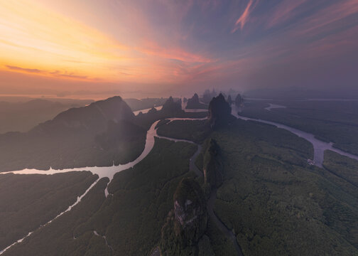 Aerial view of serene Khao Ma Chu with winding river and lush mountains at twilight, Mueang Phang Nga, Thailand.