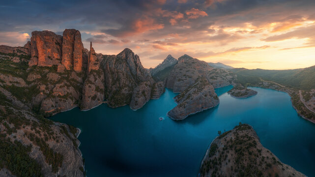 Aerial view of tranquil Vadiello lake surrounded by majestic mountains and scenic rock formations at sunset, Loporzano, Spain.