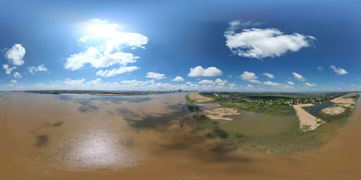 Aerial view of tranquil river reflecting sunlight under a vast sky with clouds over a picturesque village, Akreiy Ksatr, Kandal, Cambodia.