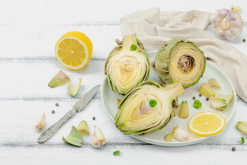 Fresh green artichokes cooking on wooden background. Traditional seasonal ingredients