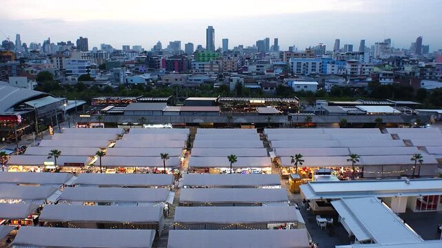 BANGKOK, THAILAND - AUGUST 2024 : View of &ldquo;The One Ratchada night market&rdquo; in sunset. High angle 4K time lapse shot, dusk to night.