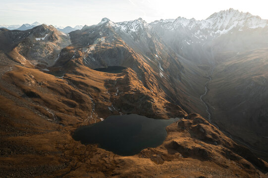 Aerial view of serene Lacs de Fenetre with majestic mountains and a tranquil river in autumn, La Fouly, Switzerland.