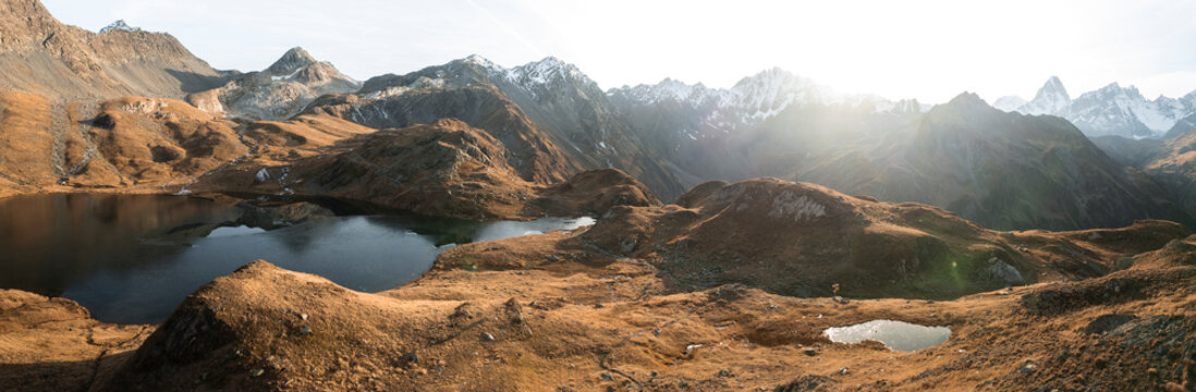 Aerial view of lacs de fenetre with majestic mountains and a serene lake at sunset, La Fouly, Switzerland.
