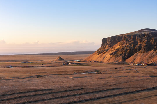 Aerial view of majestic Petursey mountain and rugged coastline at sunset, Vik i Myrdal, Iceland.