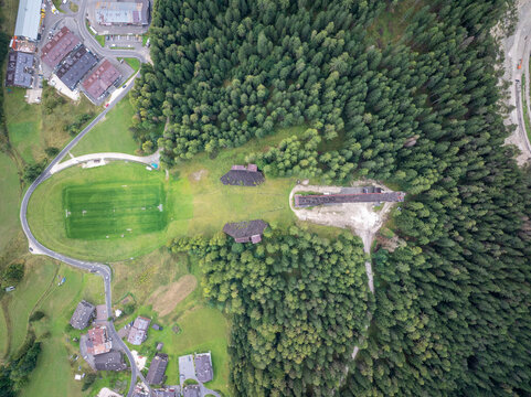 Aerial view of olympic park surrounded by lush green forest and residential buildings, Cortina d'Ampezzo, Italy.