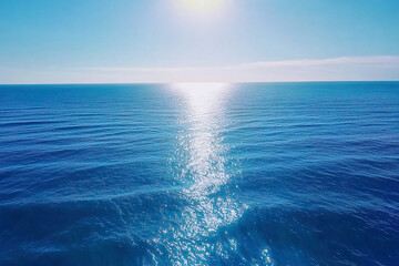 Fototapeta premium Waves ripple gently across a vibrant blue ocean under a clear sunny sky