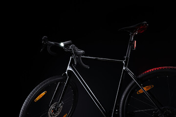 Black gravel bicycle with illuminated light on dark background.