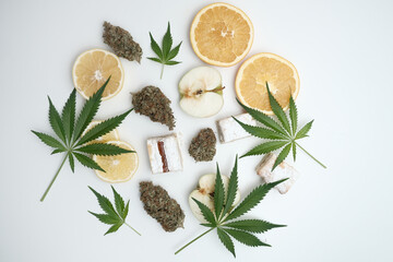 Cannabis buds with leaves and sliced lemon, apple, orange, milky cake. Marijuana terpene concept on white background