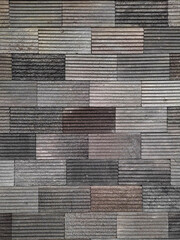 This image shows a textured brick wall with rectangular gray blocks arranged in a structured pattern. The horizontal grooves add depth and a modern architectural style.