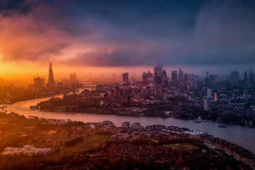 Dramatic sunset behind the urban skyline of London, England, with sun, clouds and fog