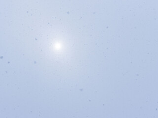 雪が降り注ぐ空とボンヤリとした太陽
