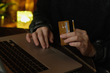 Online payments, money transfer online. Woman with bank card in her hands uses laptop to pay for online orders