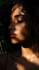 Artistic portrait in natural sunlight showcasing beautiful dark skin texture and curly hair, with dramatic shadows from palm leaves creating a mesmerizing play of light and darkness on serene face.