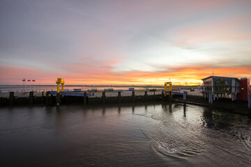 Fototapeta premium Landscape near Dagebüll harbor. Nature with sunrise on the North Sea coast. Rising sun on the sea. 