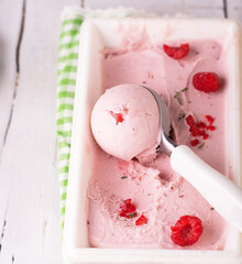 Homemade Raspberry Ice Cream Taken from the Container on a White Wooden Table.