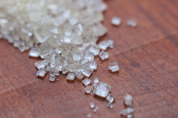 Close up macro of granulated sugar on a wooden table.